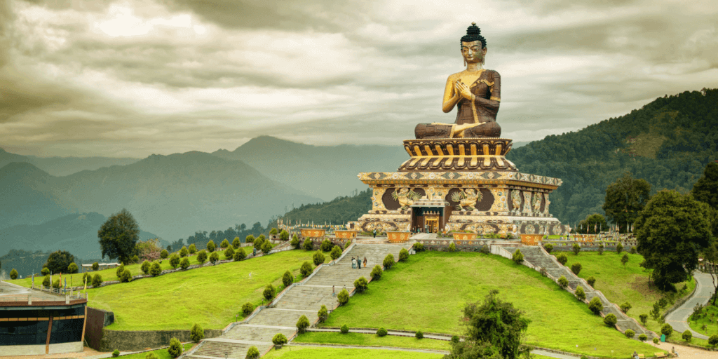 這張圖片展示了位於印度錫金的巨大佛像,這座佛像坐落於山巔,背景是壯麗的山脈。佛像的精美雕刻與周圍的自然風光相得益彰,傳遞出一種寧靜與崇高的氛圍。